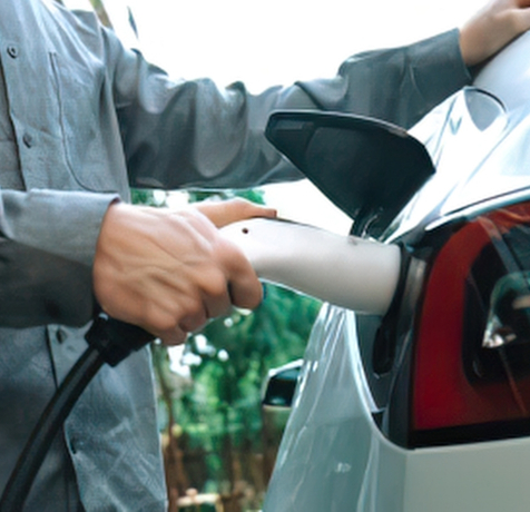 Persona cargando su vehículo eléctrico en casa